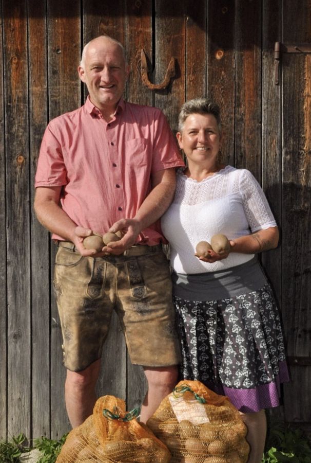 Thomas und Petra Kerschhaggl mit Kartoffeln vor der Holztür am Hof